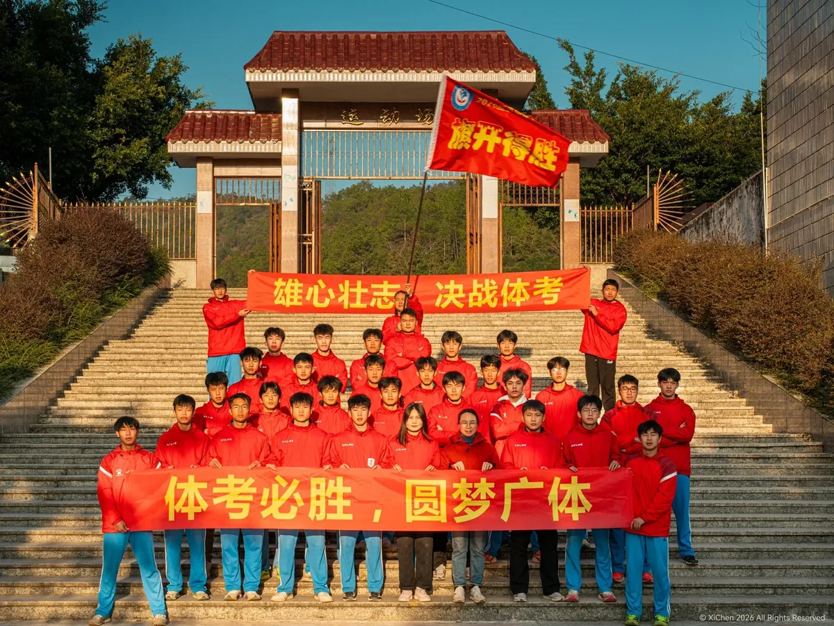 师生在学校运动场门前阶梯上合影，举起「雄心壮志 决战体考」横幅
