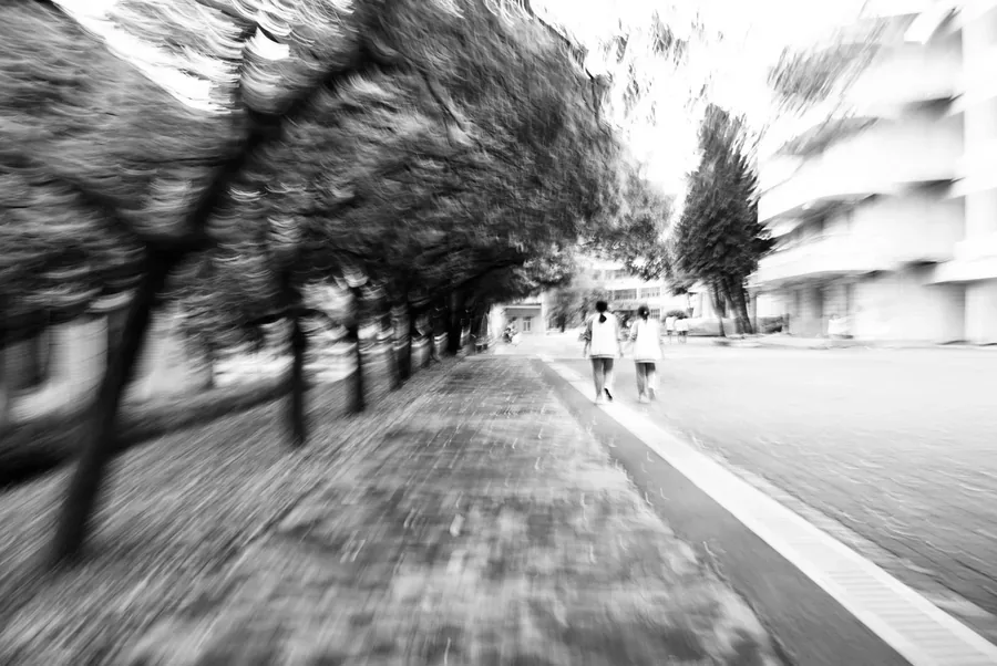 运动模糊的街道，两名行人沿道路远去